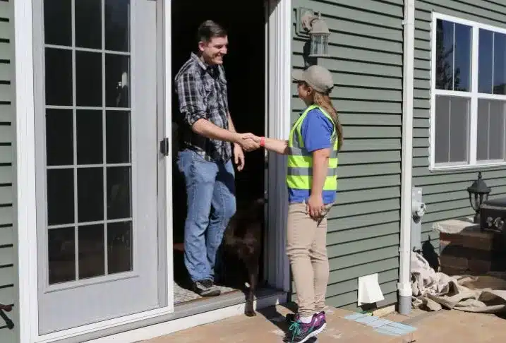 A man standing at the open patio door of his home shaking hands with a Pet Butler professional.