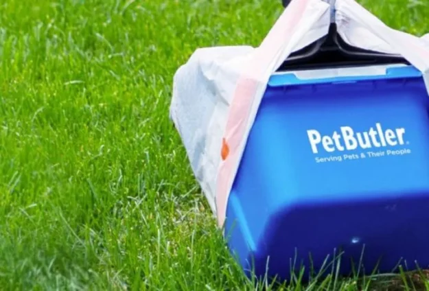 Pet Butler logoed blue bucket with a handle on the grass.