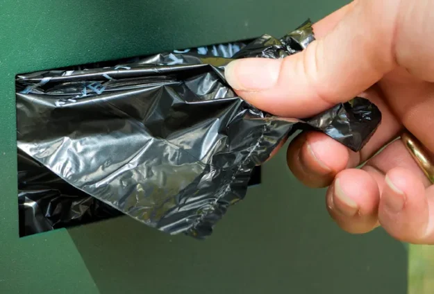 Small black plastic bag being pulled from a roll on a Pet Butler pet waste station.
